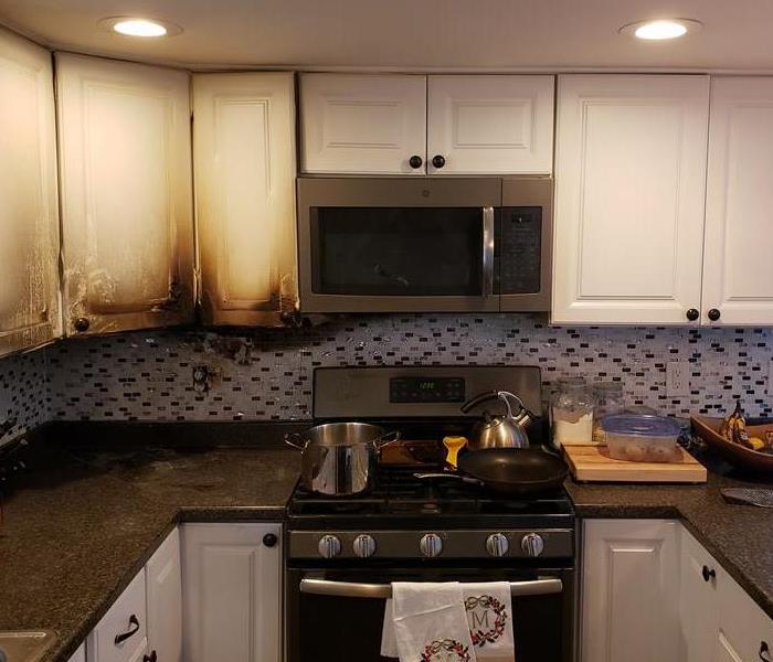 A kitchen with fire damage as a result of a stove top left unattended